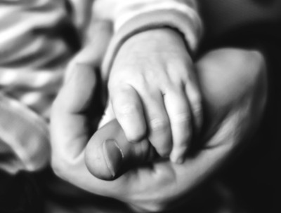 black and white photo of an infants hand in an adult male hand