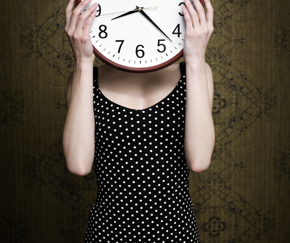 women holding clock in front of face